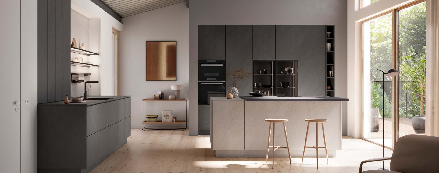 Moderne Häcker Designküche in Betonoptik mit Kücheninsel und Barhockern, grifflose Fronten und klare Linien, offene Wohnküche mit natürlichem Licht