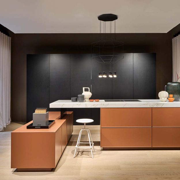 Moderne Häcker Designküche mit Kücheninsel in Orange und schwarzer Rückwand, grifflose Fronten und hochwertige Materialien in stilvollem Ambiente