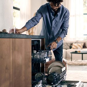 Siemens Geschirrspüler im Einsatz, integriertes Einbaugerät mit herausziehbarem Korb, komfortables Einräumen von Geschirr, modernes Küchendesign mit Holzfronten und wohnlicher Atmosphäre